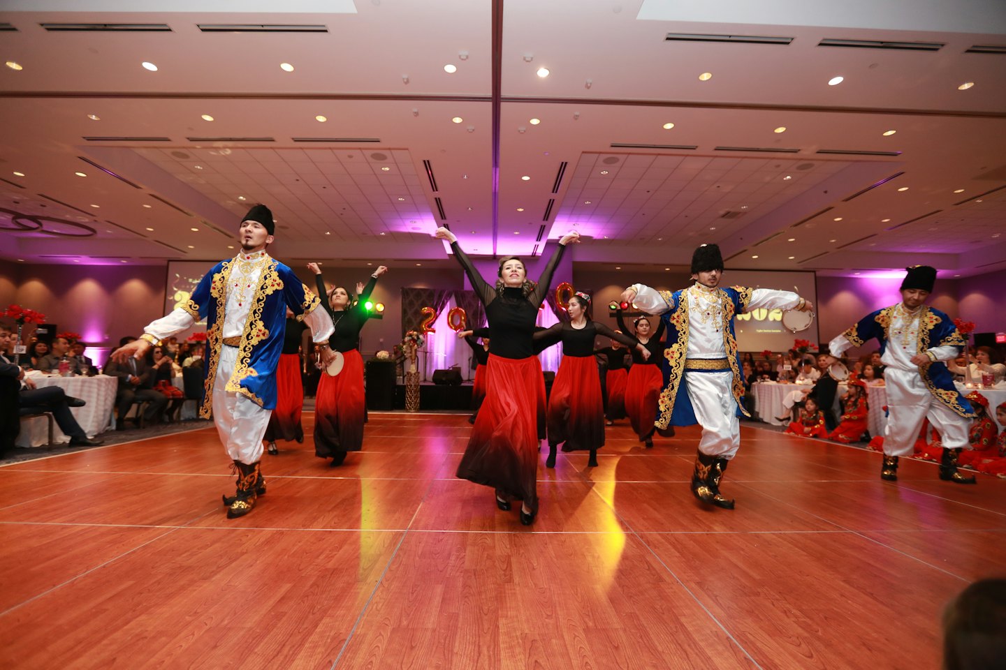 Dancers in traditional costumes perform on a wooden stage.