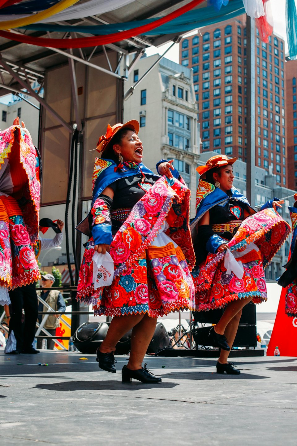 Two women perform a traditional dance on an outdoor stage.
