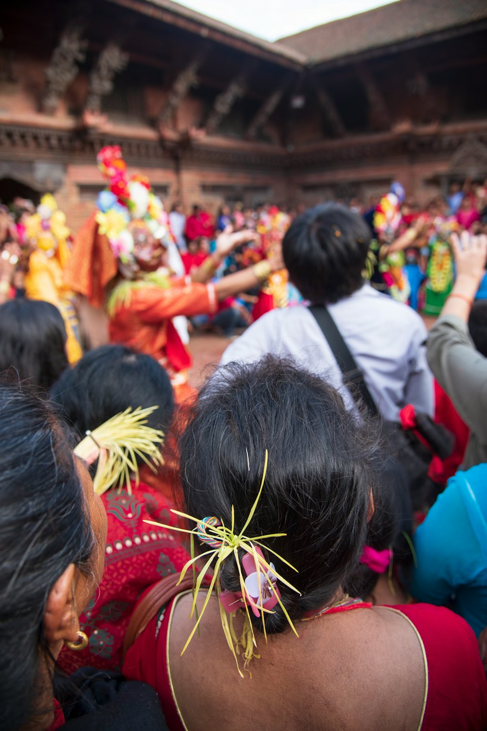 Masked dancers perform in costumes before an observant crowd.