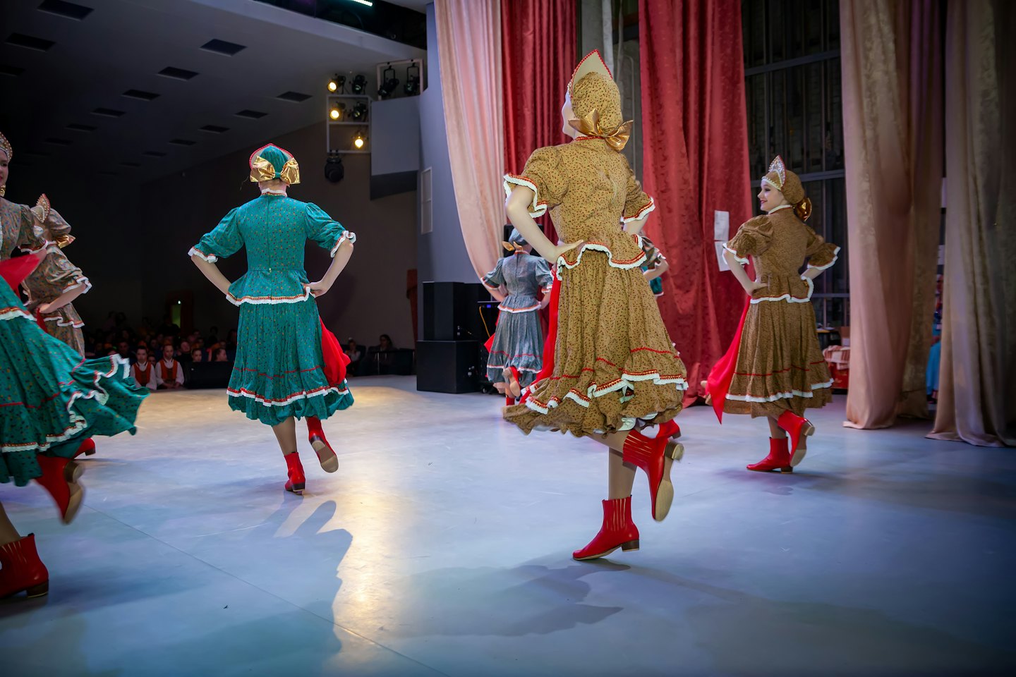 Dancers in traditional folk costumes perform on a stage.